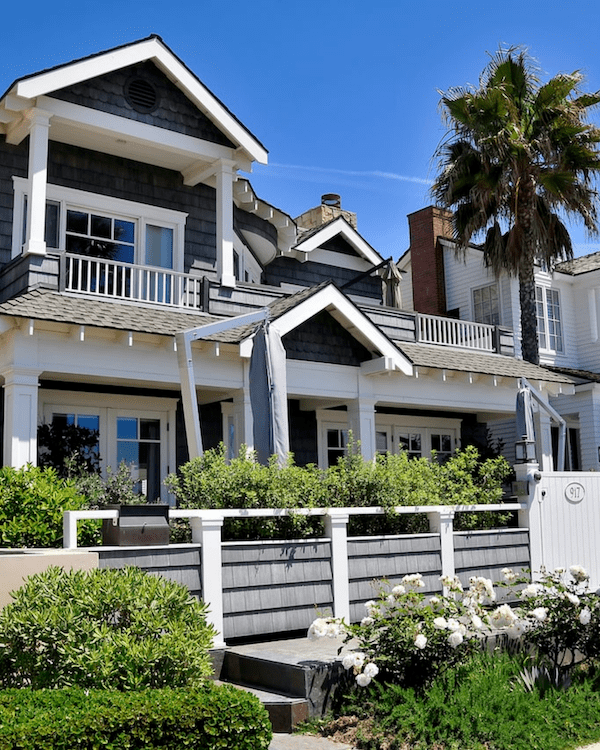 The front exterior of a craftsman cape cod style home with dark gray shingles and white trim